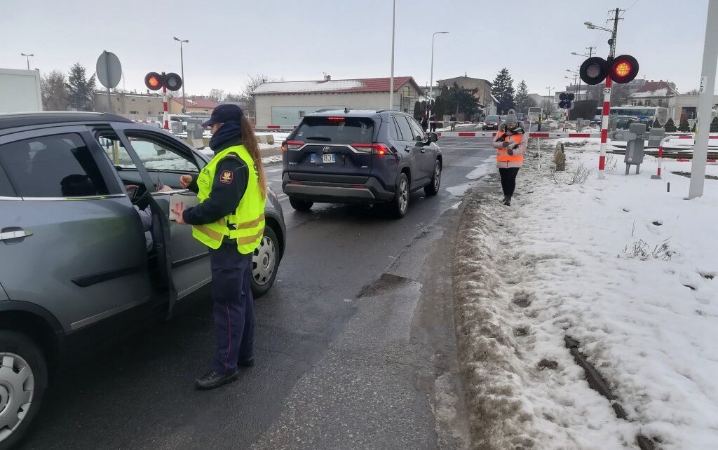 Przedstawiciele PLK i SOK wręczają ulotki kierowcom przed przejazdem kolejowo-drogowym w Tucholi (fot. Przemysław Zieliński / PKP PLK)